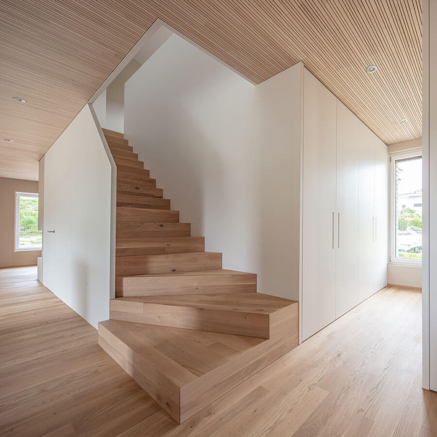 Treppenaufgang ins Obergeschoss. Boden und Treppe im gleichen Holz, Treppenwand und Schrankkubus ist weiss.