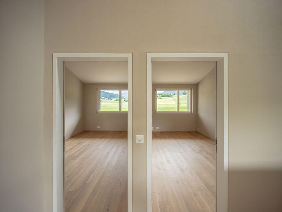 Türen und Fenster in weiss in Kontrast zu den sandfarbenen Wänden. Aussicht ins Grüne bei den Zimmerfenstern.
