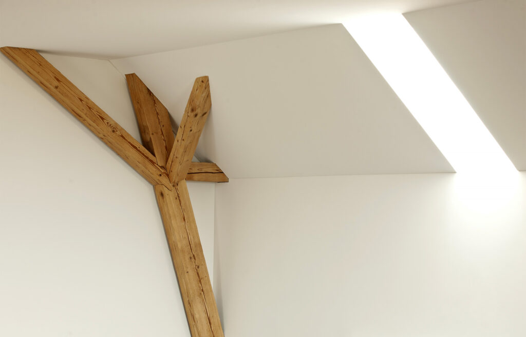 Komplexer Holzträger in Kombination mit dem licht aus dem Dachfenster.